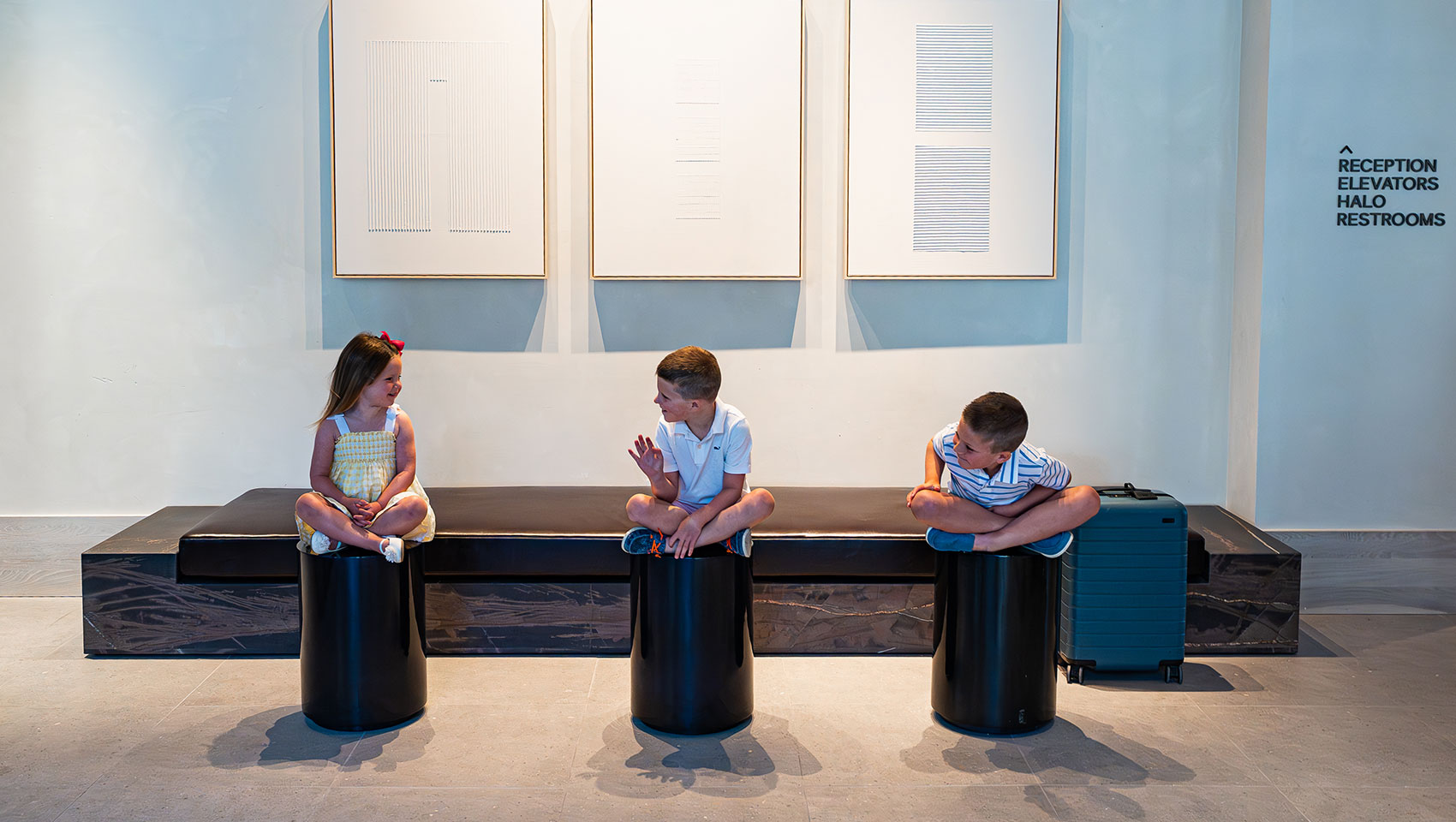 three kids sitting on stools in Claret's lobby