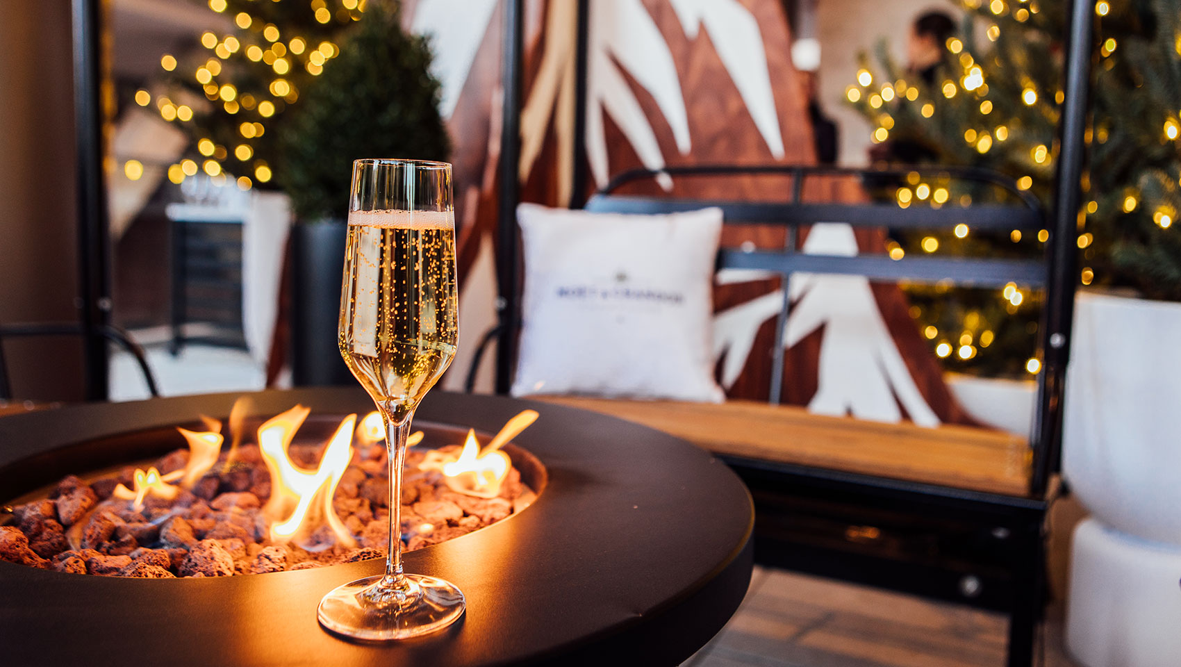 Fire pit with champagne glass and ski lift chair seating in the background