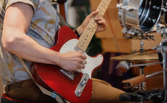 musician with red guitar and drum set in the background