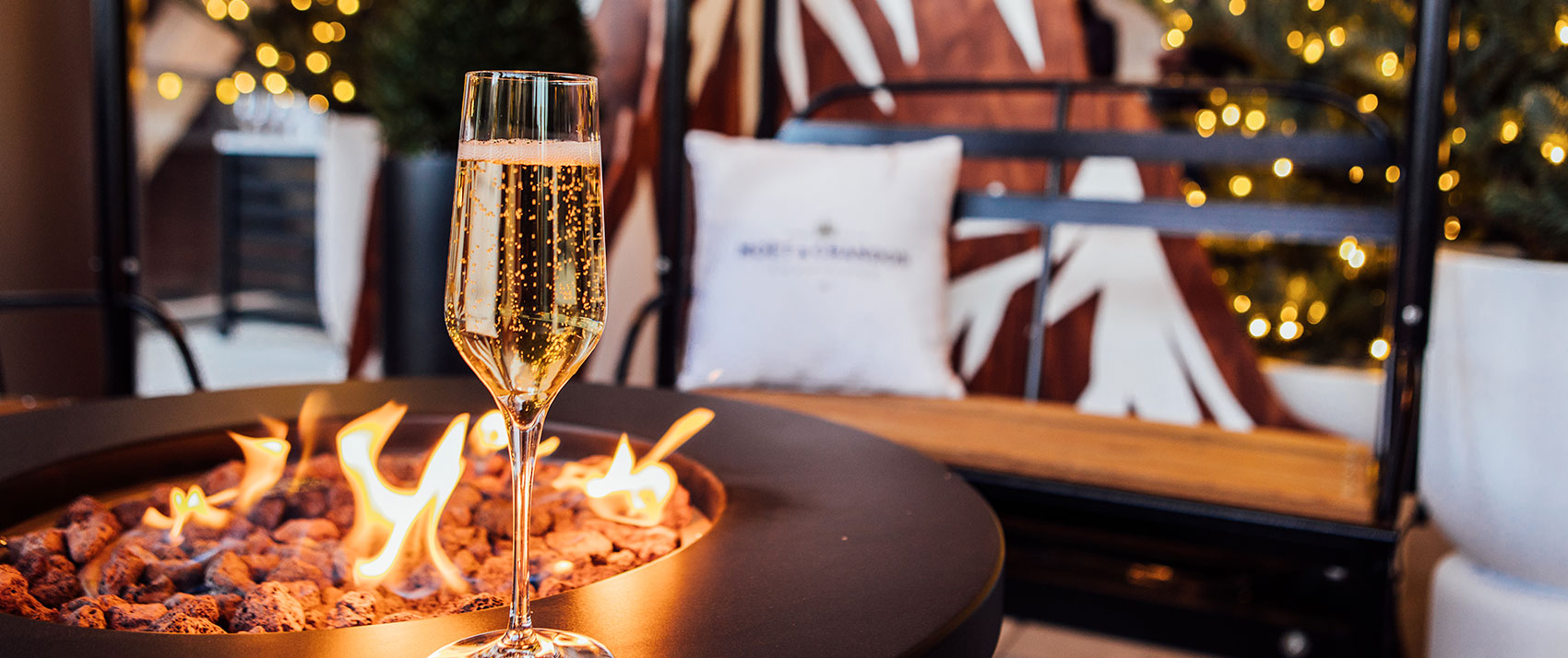 Fire pit with champagne glass and ski lift chair seating in the background